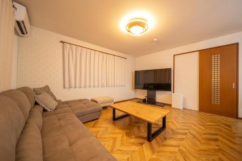 a living room with a couch and a flat screen tv at アリュール別府 in Beppu