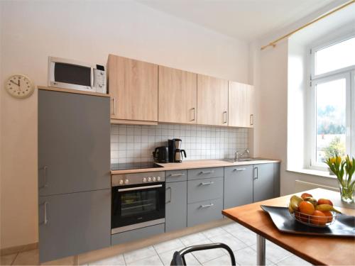 a kitchen with stainless steel appliances and a table with a bowl of fruit at Villa in Borstendorf nahe Erzgebirge in Grünhainichen
