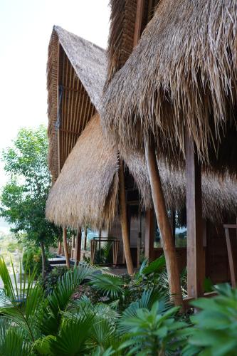 a building with a straw roof and some plants at Sky Mountain Views in Kuta Lombok
