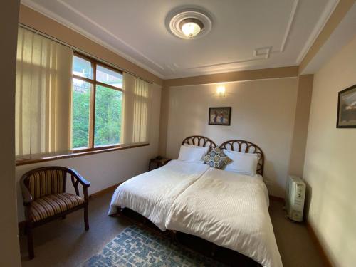 una camera da letto con un letto, una sedia e una finestra di Chansal Sky Sea 13 People - Shimla a Jāmb