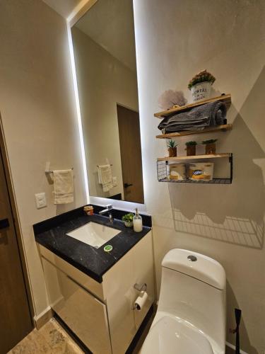 a bathroom with a toilet and a sink and a mirror at Musa 318 in Playa del Carmen