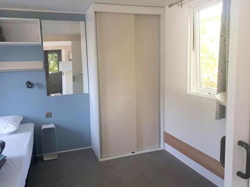 een kamer met een deur, een raam en een bed bij Mobil home 6 pers PMR avec terrasse à Chaillé-les-Marais - API-1-52-343 in Chaillé-les-Marais