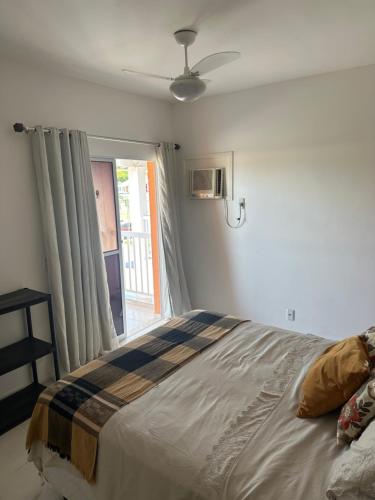 a bedroom with a bed and a window with a ceiling fan at Village Ducado in Mangaratiba