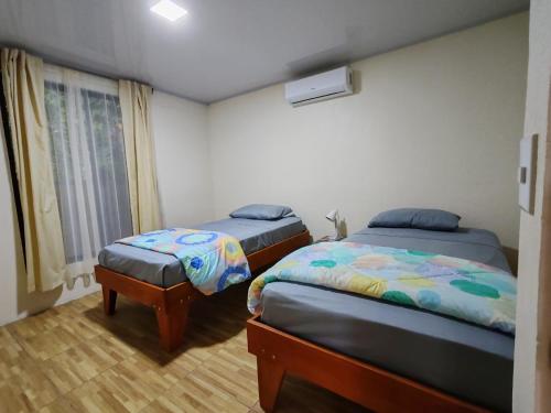 a bedroom with two beds and a window at Villas Los Titos in La Fortuna in San Francisco