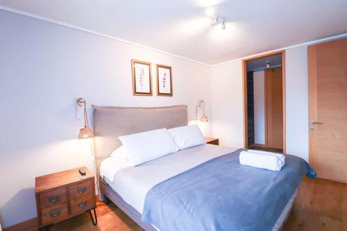 a bedroom with a bed with a blue blanket and a table at HOM I Conjunto frente a la Costanera 2D2B in Puerto Varas