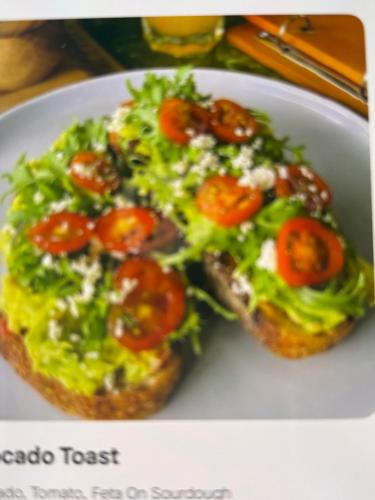 a plate with a pizza with tomatoes and lettuce at villa Angin in Munggu
