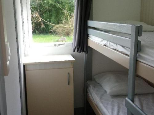 Cette petite chambre comprend des lits superposés et une fenêtre. dans l'établissement Chalet 6 pers avec Terrasse - Cuisine équipée - API-1-52-539, à Dévillac