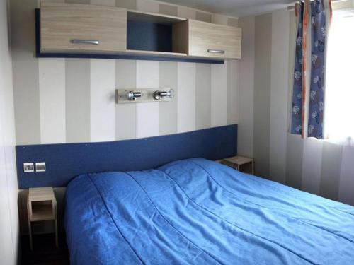 a bedroom with a blue bed with a blue blanket at Mobil-home confortable avec terrasse - API-1-52-524 in Brétignolles-sur-Mer