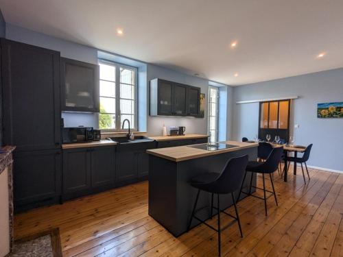 a kitchen with black cabinets and bar stools at Maison Ivaldi - FR-1-653-280 in Jarnac