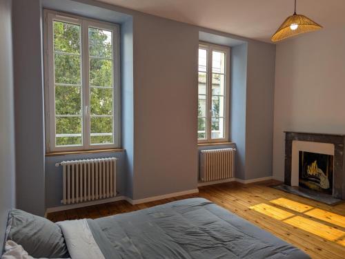 a bedroom with a bed and two windows and a fireplace at Maison Ivaldi - FR-1-653-280 in Jarnac