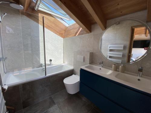 bagno con vasca, servizi igienici e specchio di Chalet 5 Chambres avec Wifi et Parking aux Gets - FR-1-671-299 a Les Gets