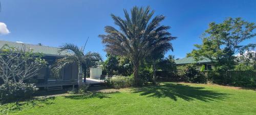 a house with palm trees in a yard at Fare Coco Tiaré - Jardin Tropical Piscine - Moorea in Afareaitu