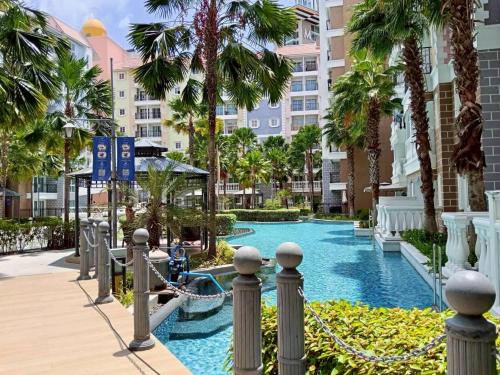 une piscine au milieu d'un complexe avec des palmiers dans l'établissement Blue lagoon seven sea jomtien, à Na Jomtien