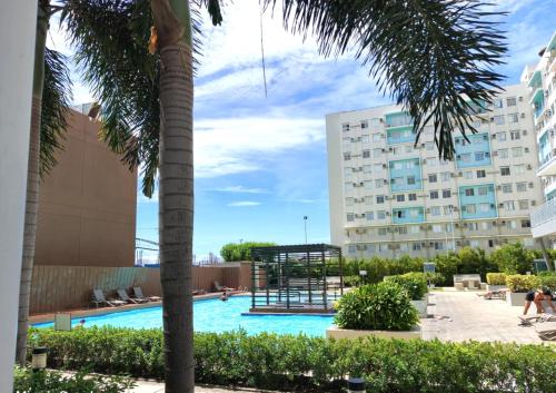 a swimming pool with a palm tree and a building at Mistow MarinaSpatial Dumaguete in Piapi