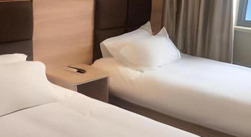 two beds with white sheets and a pillow at Shanghai Jiejia hotel in Shanghai