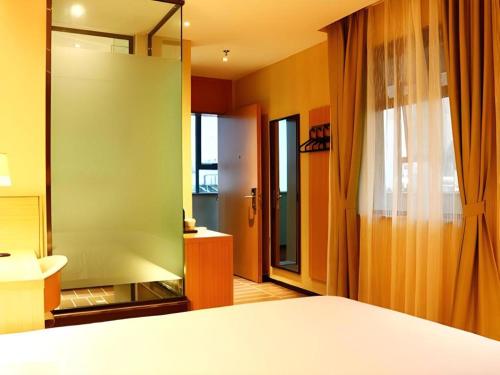 a room with a bed and a bathroom with a mirror at IU Hotel Kunming Jinma Bijifang Joy City in Kunming