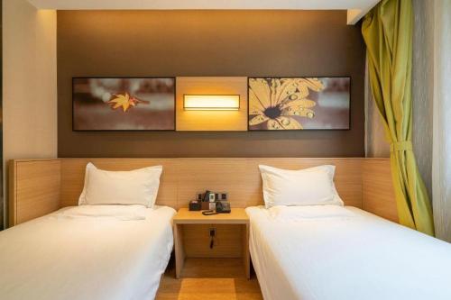 two beds in a room with a desk and two beds at IU Hotel Kunming Jinma Bijifang Joy City in Kunming