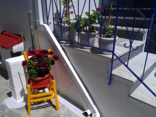 a balcony with potted plants and a yellow chair at Amfi Apartments in Kardamaina