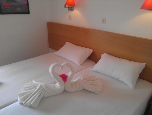 two swansrendered to look like hearts sitting on a bed at Amfi Apartments in Kardamaina