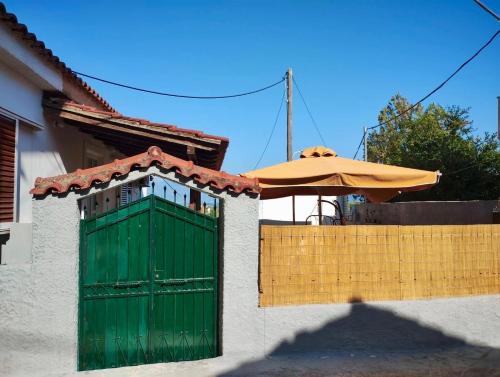 a green door and an umbrella next to a fence at Aμvrosia Avramio Village - Fireplace, Free WiFi, Pet Friendly in Avramión