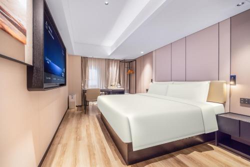 a bedroom with a white bed and a flat screen tv at Atour X Hotel Shenzhen Luohu Dongmen Pedestrian Street in Shenzhen