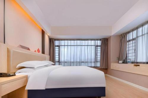 a bedroom with a large white bed and large windows at Borrman Hotel Liuzhou High-Speed Railway Station in Liuzhou