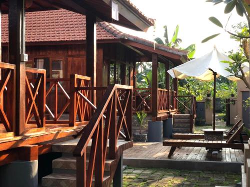 a house with a wooden deck with an umbrella at Private Pool Retreat With Two Villas, Two Kitchens, Two Bathrooms, Perfect for Families and Friends Traveling Together in Ubud