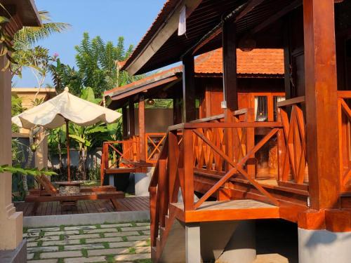 a wooden house with a porch and an umbrella at Private Pool Retreat With Two Villas, Two Kitchens, Two Bathrooms, Perfect for Families and Friends Traveling Together in Ubud