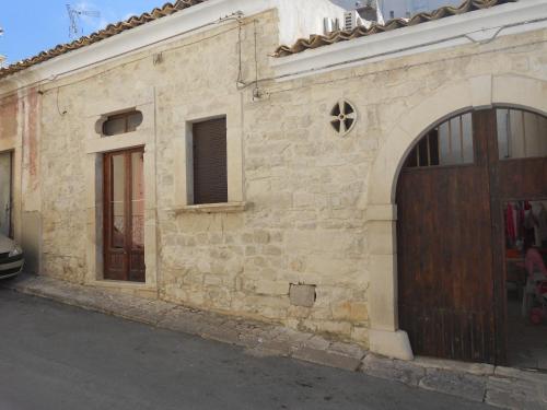 un antiguo edificio de piedra con puerta de madera en Piccola Azzurra en Comiso