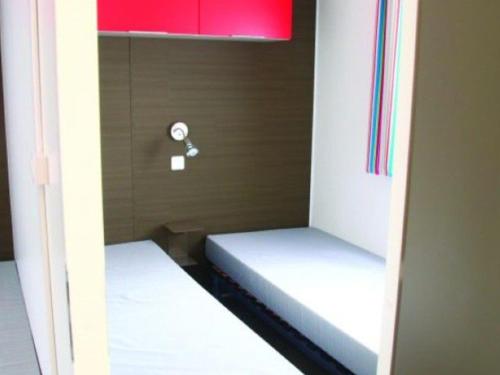 deux lits dans une petite pièce avec une fenêtre dans l'établissement Mobil home spacieux avec terrasse à Dévillac - API-1-52-234, à Dévillac