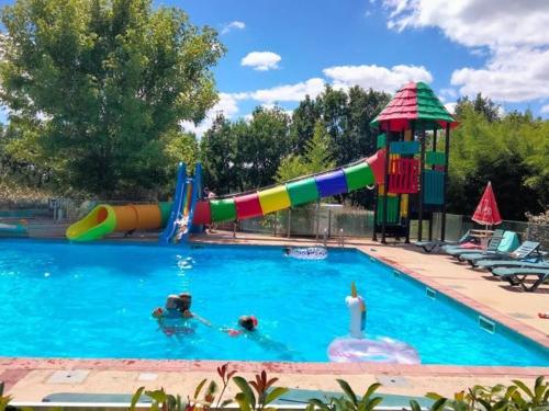 2 personnes dans une piscine avec toboggan dans l'établissement Mobil home spacieux avec terrasse à Dévillac - API-1-52-234, à Dévillac