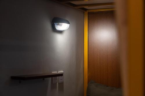 a light on the wall of a room with a bed at Pondok Tis Bisma in Ubud