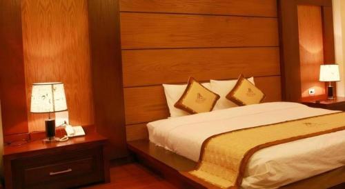 a bedroom with a bed with a wooden headboard and two lamps at Duy Anh Hotel in Hải Dương