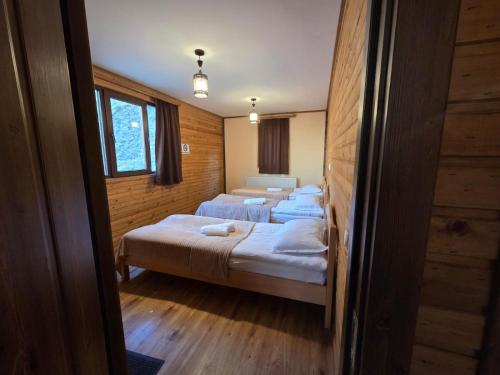 three beds in a room with wooden walls at Gergeti Woods in Stepantsminda