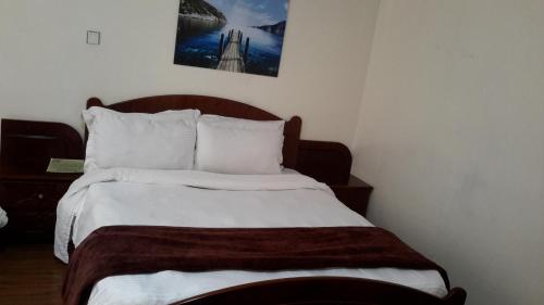 a bedroom with a bed with white sheets and pillows at DV Guest House 2 in Addis Ababa