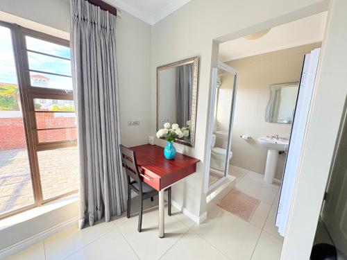 a bathroom with a desk and a mirror at Le Blue Guesthouse in Port Elizabeth