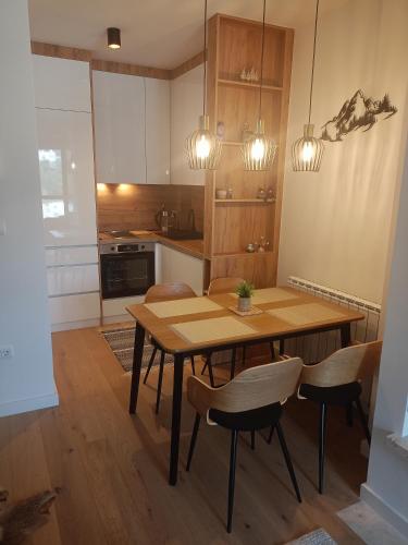 a kitchen with a wooden table and chairs at A-Apartman in Bjelašnica
