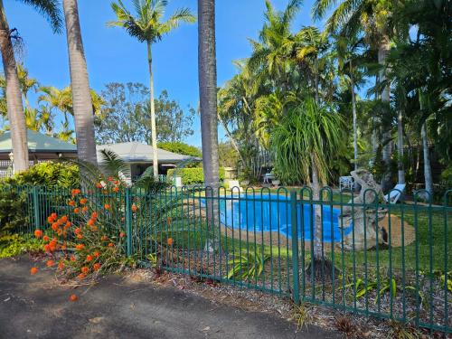 a green fence with flowers in front of a pool at Cleveland Motor Inn in Cleveland