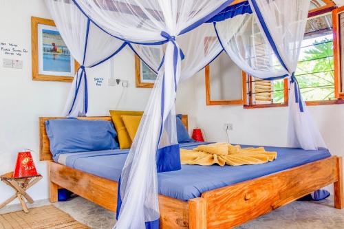 a bedroom with a canopy bed with blue sheets at Kameleon Blue in Kizimkazi