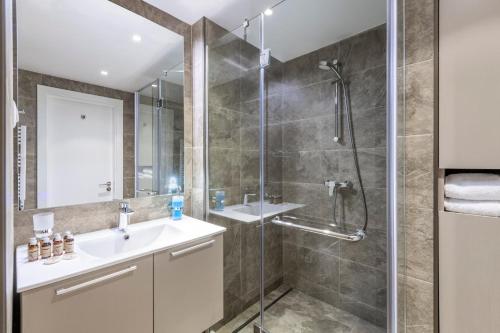 a bathroom with a shower and a sink and a mirror at Alliance Palace in Marriott in Batumi
