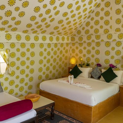 a bedroom with two beds with yellow flowers on the wall at desert Galaxy Camp Jaisalmer in Jaisalmer