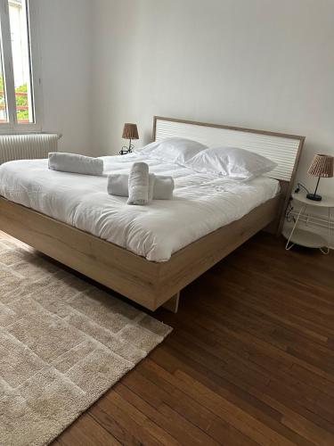 Un dormitorio con una cama con sábanas y almohadas blancas. en Le Cocon de la Gare, en Saint-Pierre-des-Corps