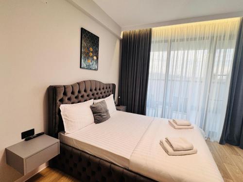 une chambre avec un grand lit avec une grande fenêtre dans l'établissement COZY Apartment - Titu Maiorescu Residence, à Bîrlad