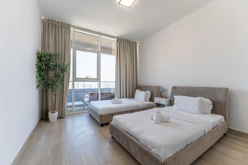 a bedroom with two beds and a large window at HAVN - 2 Bedroom Apartment in Bloom Tower, JVC in Dubai