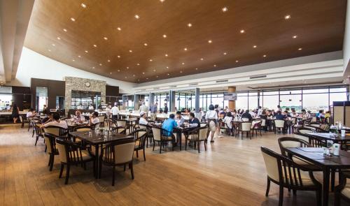 Un comedor con gente sentada en mesas en un restaurante. en The Golf Lodge Hotel Laem Chabang Golf, en Ban Nong Wa