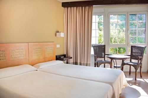 ルアルカにあるHotel La Colmenaのベッドルーム1室(ベッド1台、テーブル、椅子付)