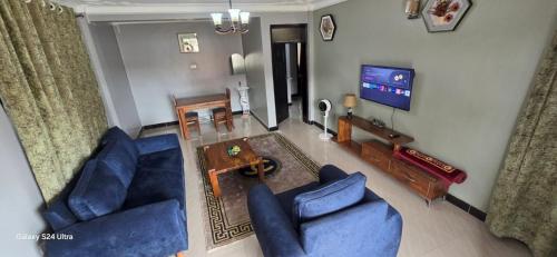 a living room with two blue couches and a television at kuza Suites Mbale in Mbale