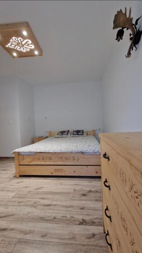 a bedroom with a bed and a wooden dresser at Tatra Lodge Apartamenty z widokiem na góry in Kościelisko