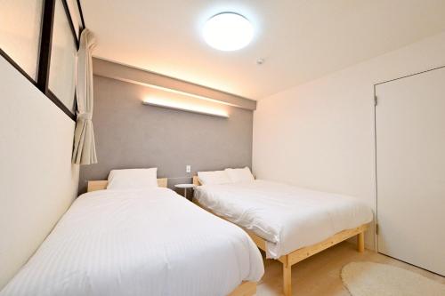 two beds in a room with white sheets at シャトーひらぎし in Sapporo