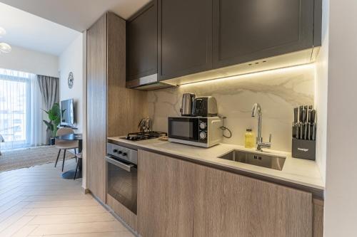 a kitchen with a sink and a microwave at HAVN - Studio Apartment in Pantheon Elysee, JVC in Dubai